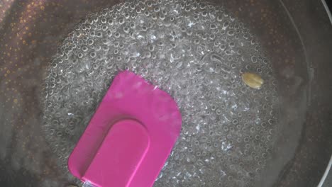 Pouring-white-sugar-in-a-glass-of-water-on-table-,