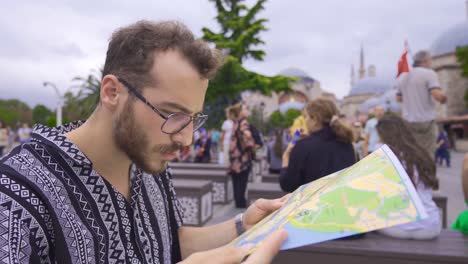 Touristenmann-Schaut-Auf-Papierkarte.