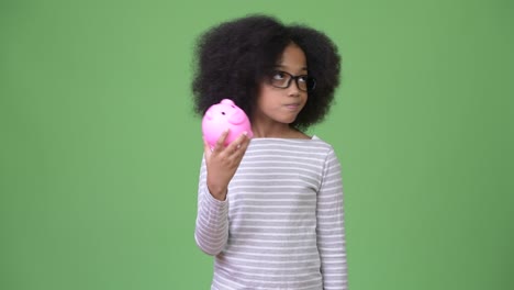 young cute african girl with afro hair holding piggy bank