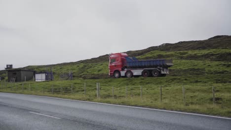 panning shot of driving truck on rural faeroese road during cloudy day on faeroe island