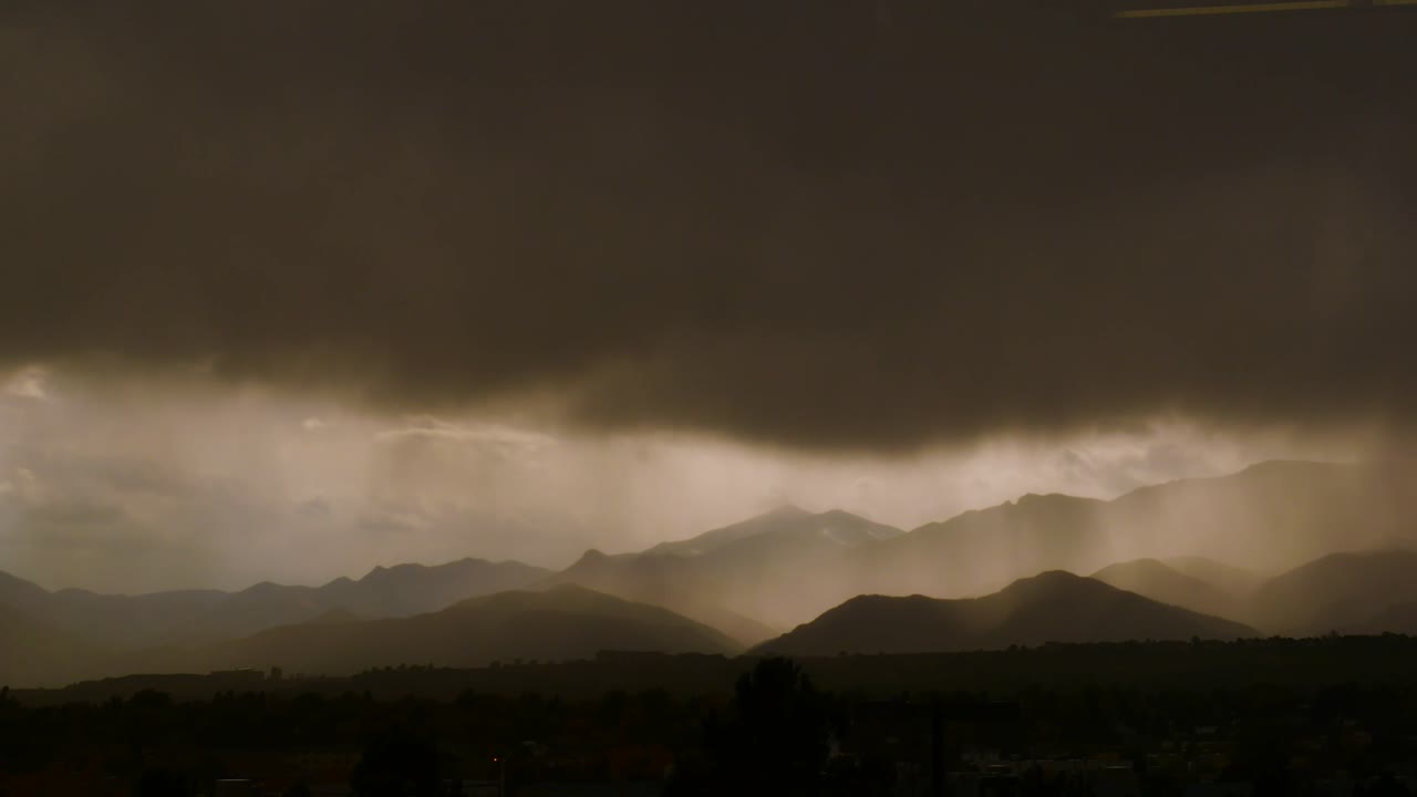 timelapse de montañas con transición de una ciudad soleada a una tormenta de lluvia 4k