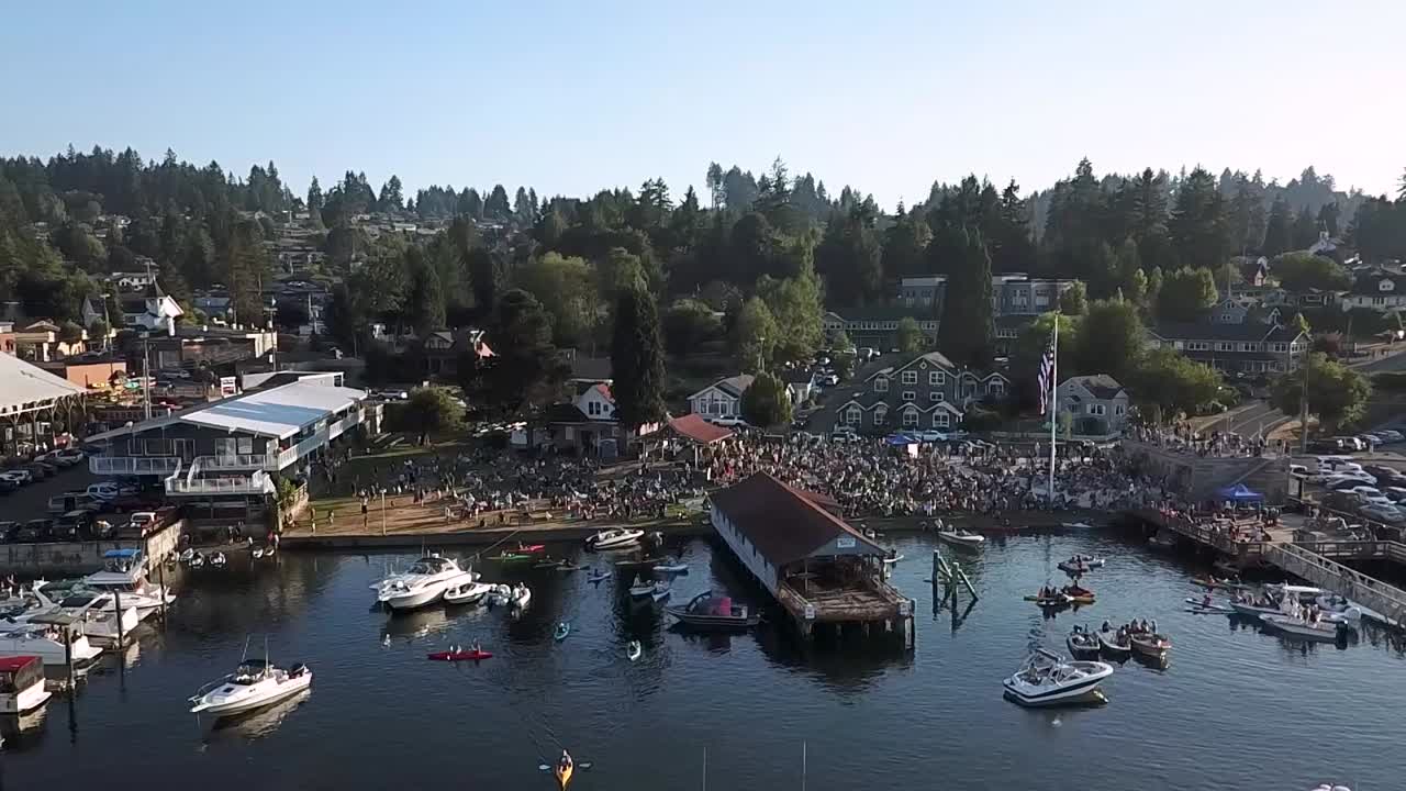 gente en el parque de los hermanos skansie y netshed durante un concierto en el puerto de conciertos, washington con yates y kayakistas en las aguas tranquilas - drone aéreo, tiro panorámico