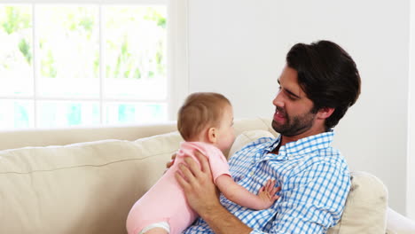 Cute-father-lying-on-sofa-playing-and-embracing-his-baby