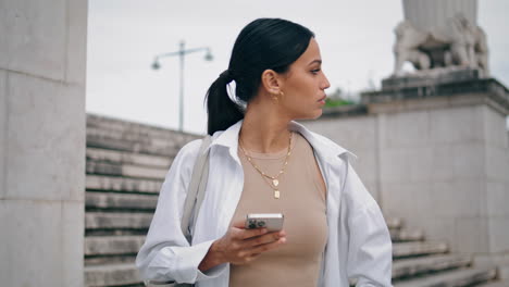 chica enojada con un teléfono inteligente esperando en la calle vertical. mujer nerviosa mirando