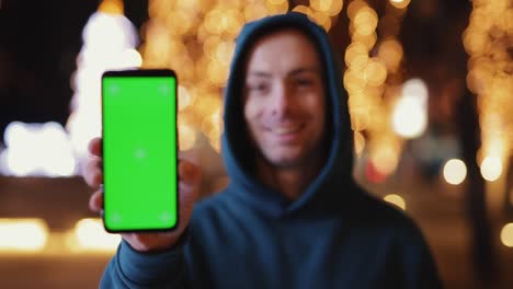 man shows empty green screen at night