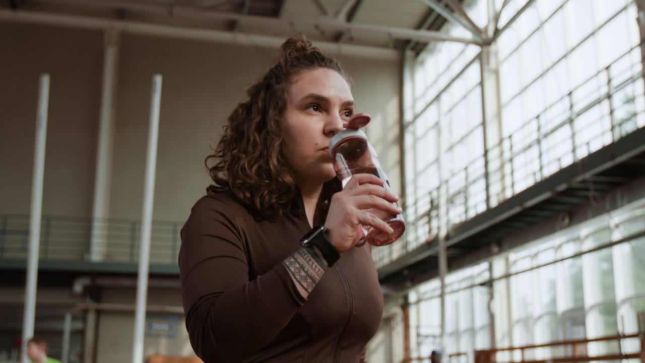 A person drinking from a water bottle in a gym
