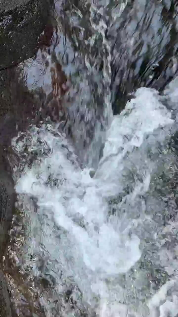 Primo piano di acqua impetuosa che scorre su rocce scure