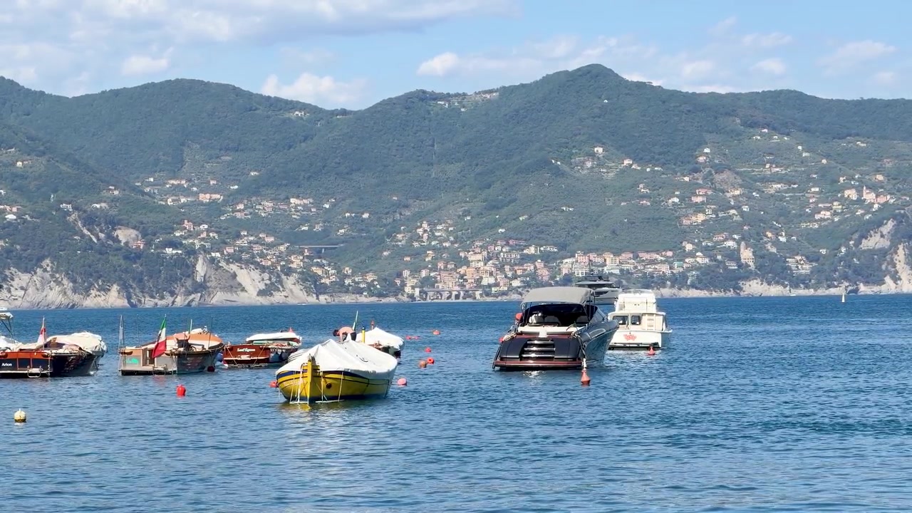 Campo lungo di yacht di lusso e motoscafi ormeggiati nelle calme acque blu della costa mediterranea.