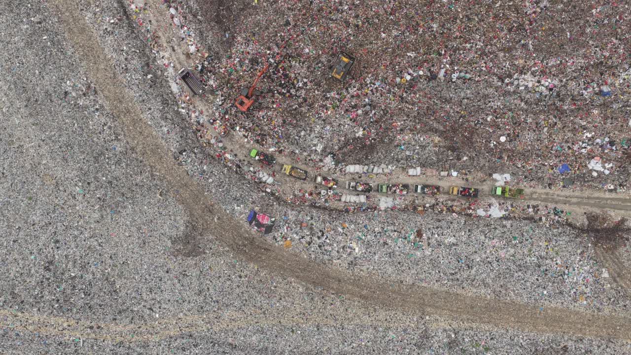 Vista aerea di camion che scaricano rifiuti in una grande discarica