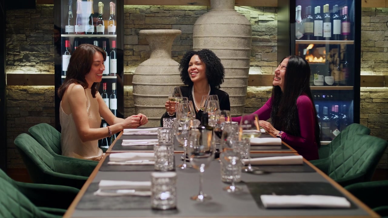 Elegant interracial group of friends sharing a joyful greeting and embracing at a luxury restaurant