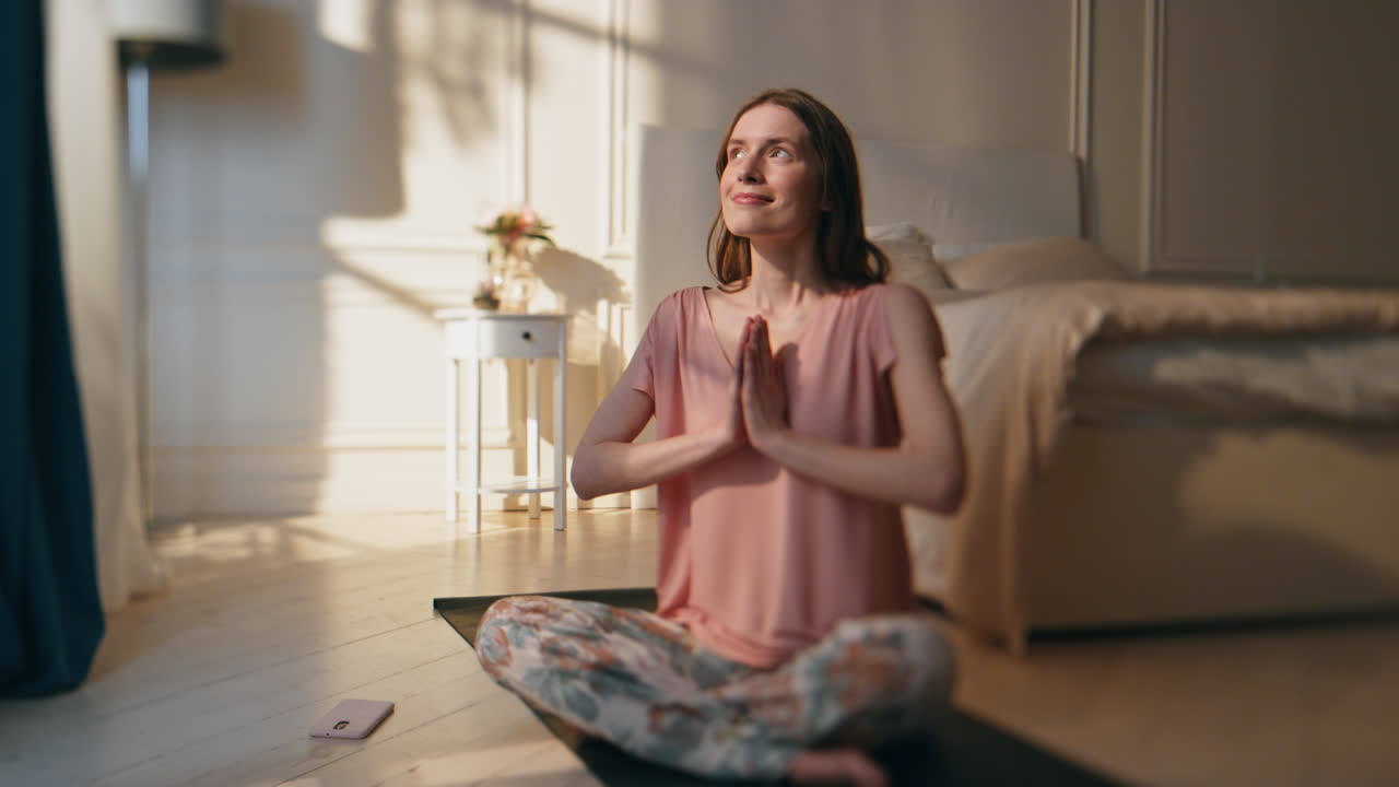 niña sonriente sentada en una asana de loto a la luz del sol de la mañana. mujer despreocupada meditando