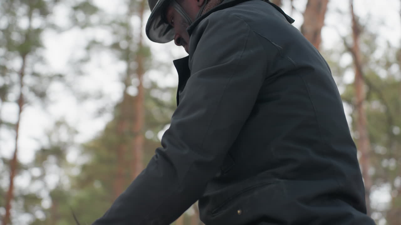 preparing equine for riding, man adjusting saddle straps outdoors, equestrian getting ready in snowy arena environment, individual securing horse tack outdoors with winter scenery in background