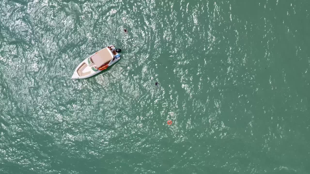 vista de arriba de un pequeño barco de turismo de delfines anclado en el agua del océano turquesa tropical con turistas nadando cerca de la famosa playa de madeiro en pipa, brasil río grande do norte