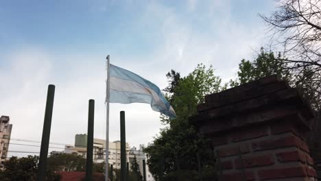 argentine flag waves in the sky with city buildings of capital city