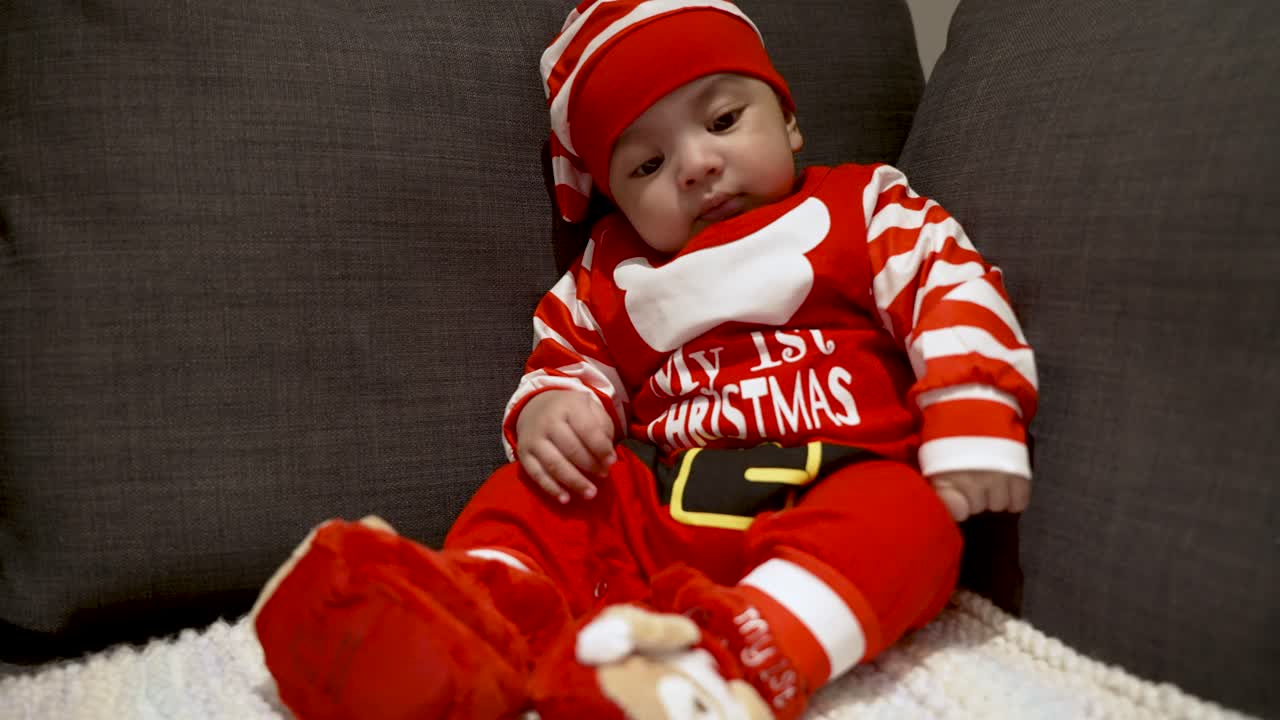adorable lindo bebé de dos meses en traje festivo rojo de navidad sentado en el sofá
