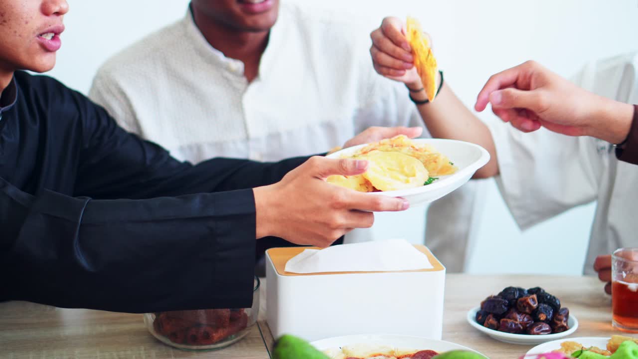 Close Up View Of Muslim Man Passing His Friends Food During Iftar on Ramadan at Dining Table