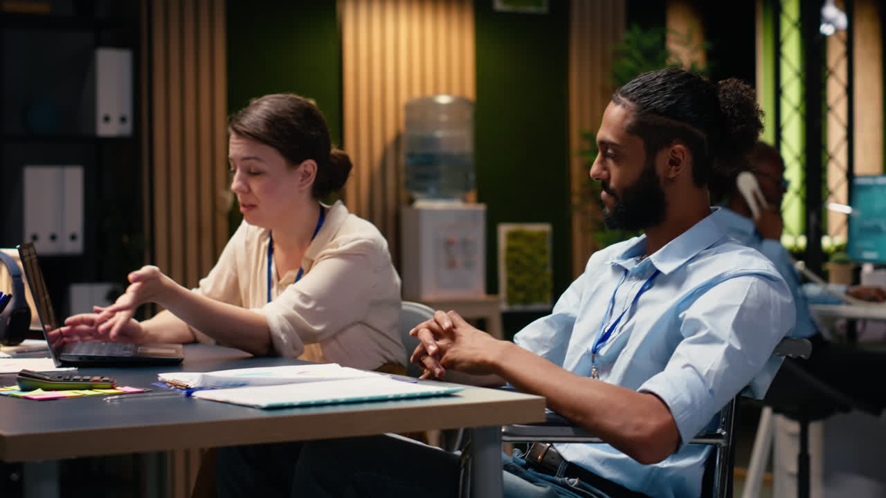 Diverse employees sharing fist bump, man with disability, success in teamwork
