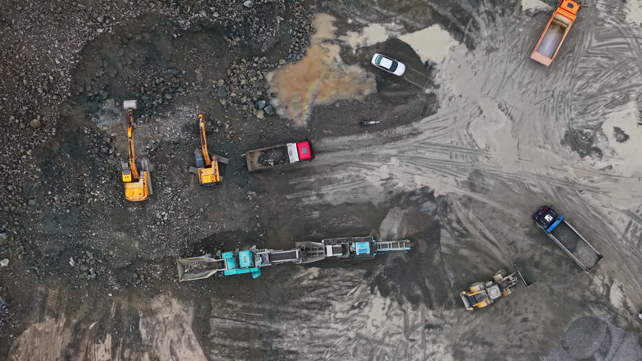Granite quarry machinery and vehicles working in a rocky site during daylight hours
