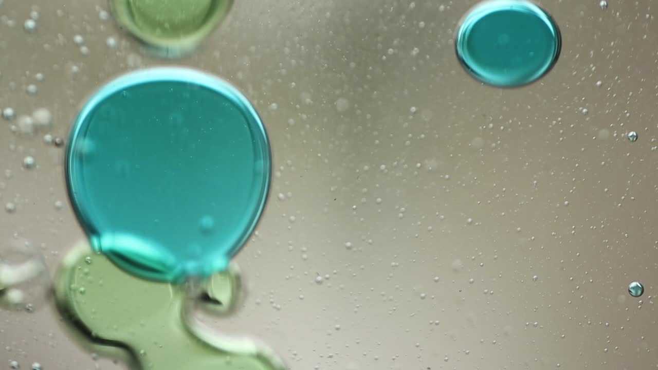 ラバランプの中で、青と緑の液体が泡や塊を浮かべながら動く様子を水平方向からクローズアップ。催眠的で抽象的な視覚テクスチャ。
