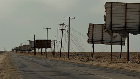 abandoned road with damaged billboards in a desert landscape