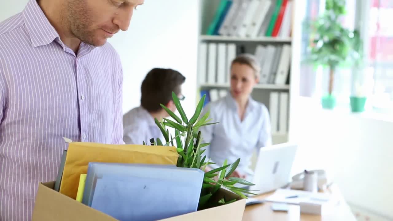 リストラされたビジネスマンが ⁇ 自分の物の箱を持っています ⁇