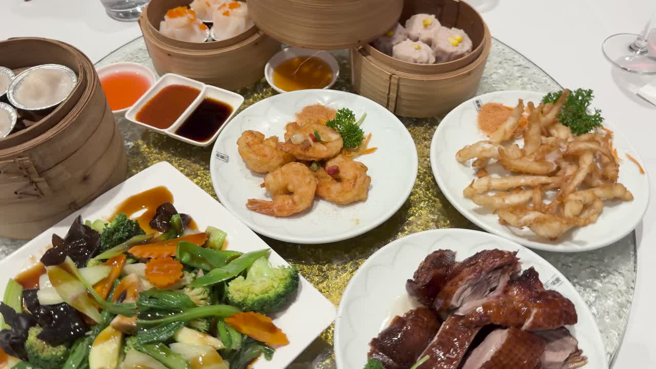 A vibrant spread of dim sum dishes on a rotating lazy Susan, featuring shrimp, roast duck, and stir-fried vegetables
