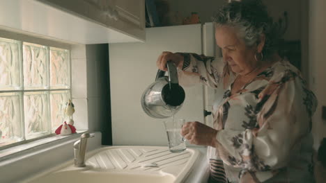 Woman-pouring-hot-water-from-kettle-in-tea-mug