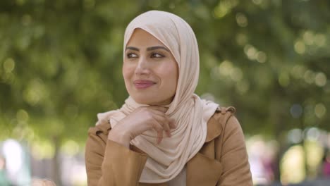 retrato de una mujer de muselina sonriente con hijab sentada en una mesa al aire libre en la calle 1 de la ciudad