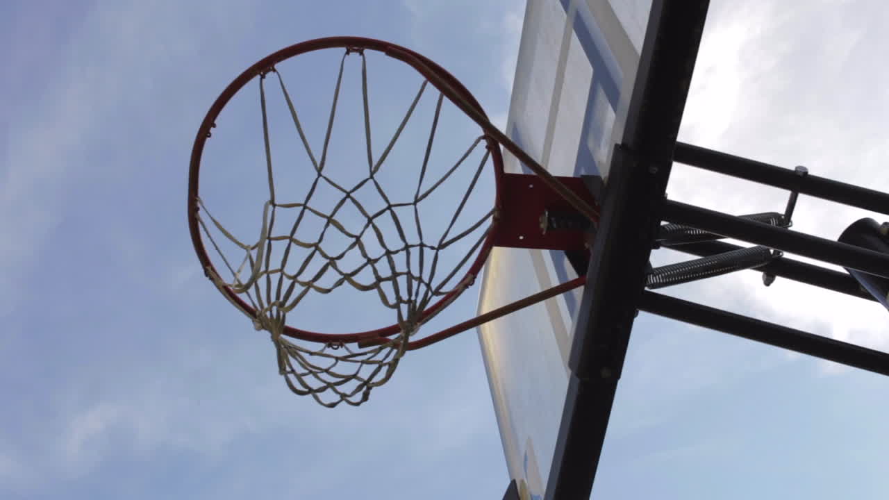 disparar una pelota en el aro de baloncesto contra el cielo azul