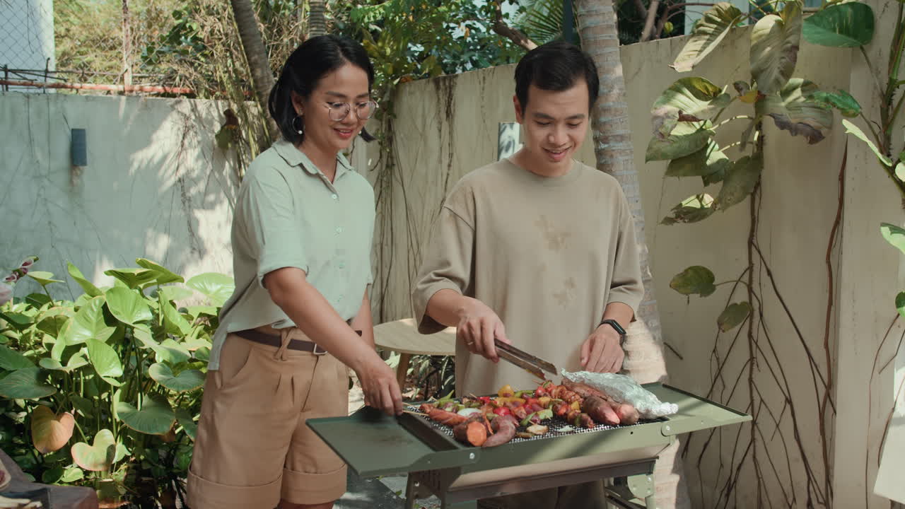 Portrait of Asian Couple Grilling Food and Smiling at Camera