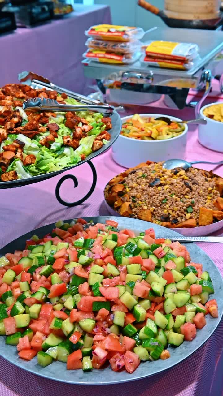 Insalata Caesar con crostini e buffet di insalata di pomodori e cetrioli. Diverse insalate servite su vassoi di metallo a un evento di catering o a un buffet di ristorante.