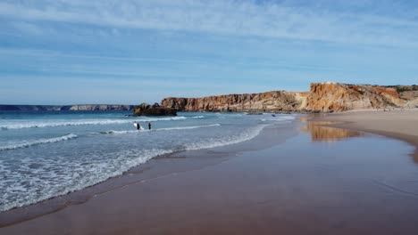 perfect white sandy beach in tonel near sagres , some surfers hit the water