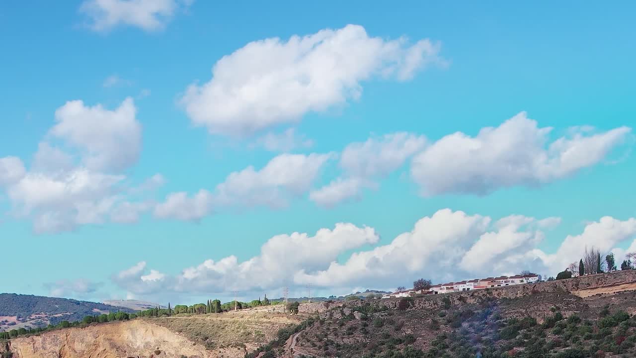 Hari cerah di Malaga dengan awan di atas bukit dan ladang