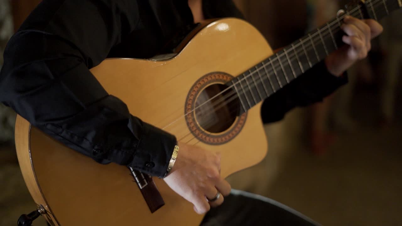 Close-up of a man strumming an acoustic guitar, fingers moving rhythmically over the strings, creating an authentic and relaxed atmosphere.