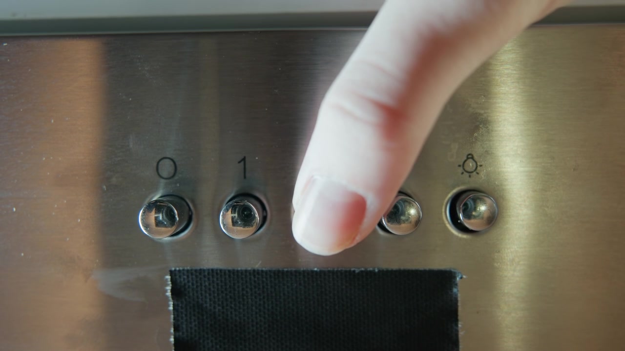 Frontal close-up of brushed stainless steel control panel showing row of four numbered circular push buttons with indicator lights above each button and dark vent opening at lower edge