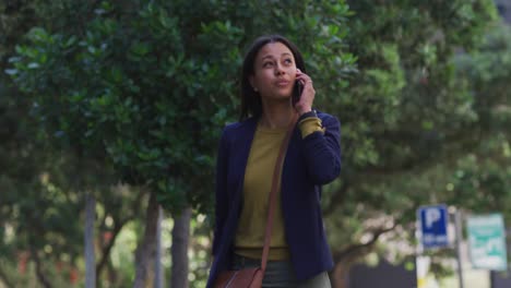 mujer afroamericana hablando en un teléfono inteligente mientras caminaba por la calle