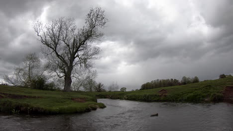 A-cold-grey-day-on-the-river-Arrow-in-Warwickshire,-England-as-rain-clouds-gather-over-this-rural-scene