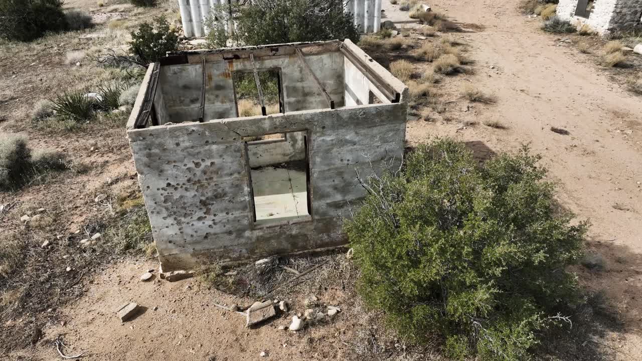edificios abandonados estructuras de hormigón destruidas por el cártel con agujeros de bala en el lado en el alto desierto del sur de california en un día nublado con un estado de ánimo apocalíptico 60fps