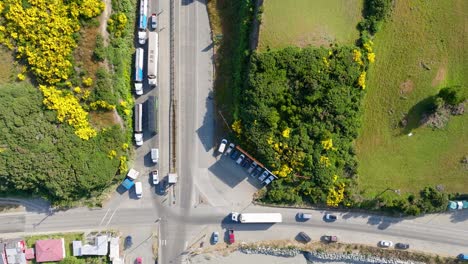 Vista-Aérea-De-Pájaro-De-Camiones-Estacionados-Que-Conducen-Al-Muelle-Con-Ferry-Esperando-En-La-Isla-Grande-De-Chiloé,-Chile