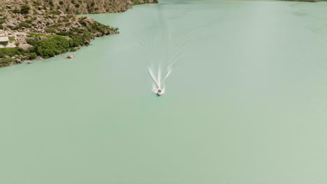 idyllic landscape of iskanderkul lake with boat in tajikistan - aerial drone shot