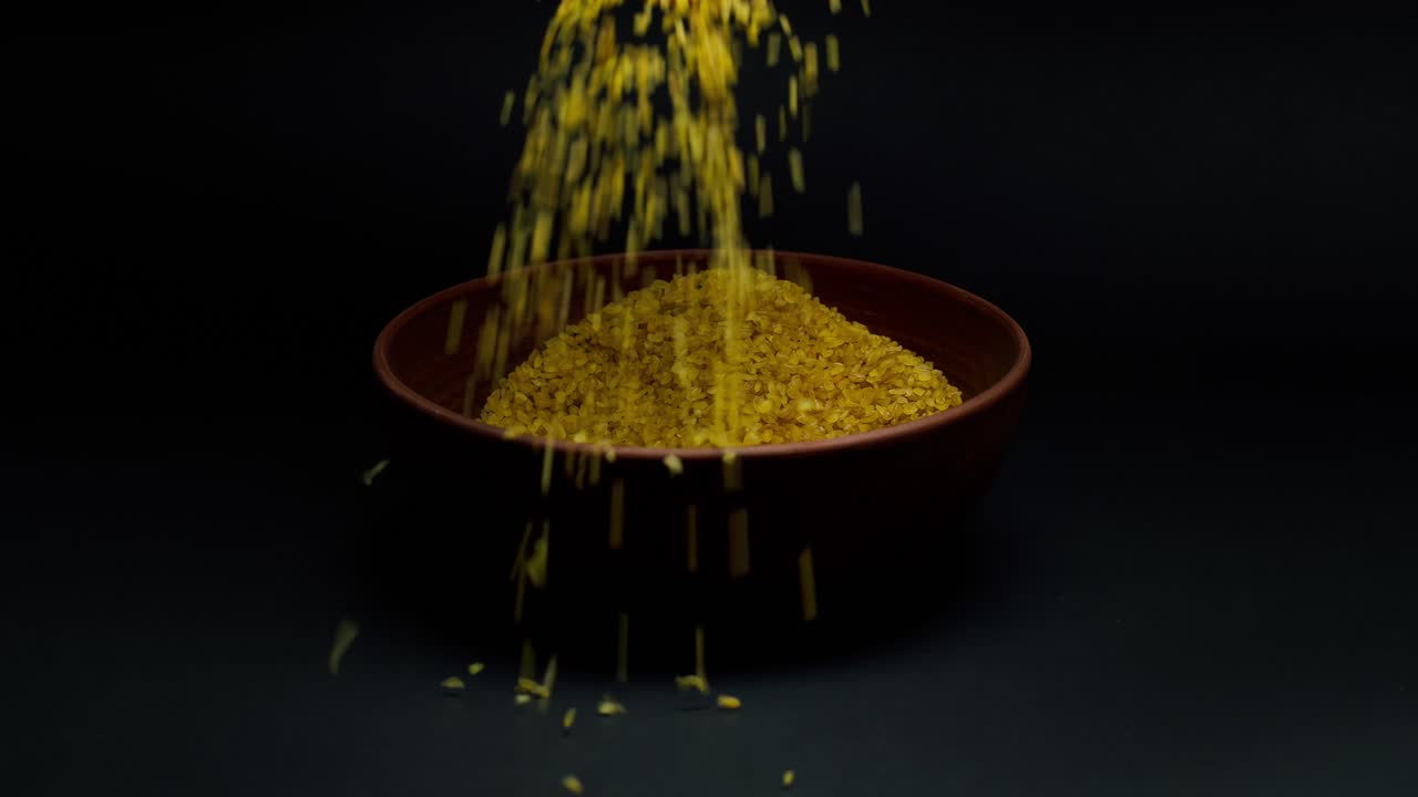 Hands Pouring Yellow Bulgur Grain into a Bowl