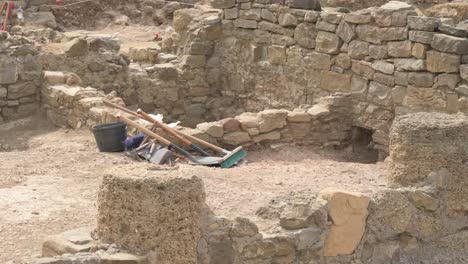 tools resting against a low wall at an archaeological excavation site