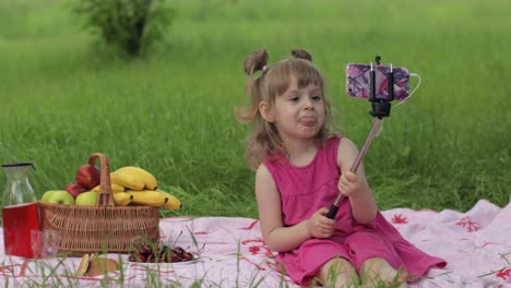 Weekend-at-picnic.-Girl-on-grass-meadow-makes-selfie-on-mobile-phone-with-selfie-stick.-Video-call