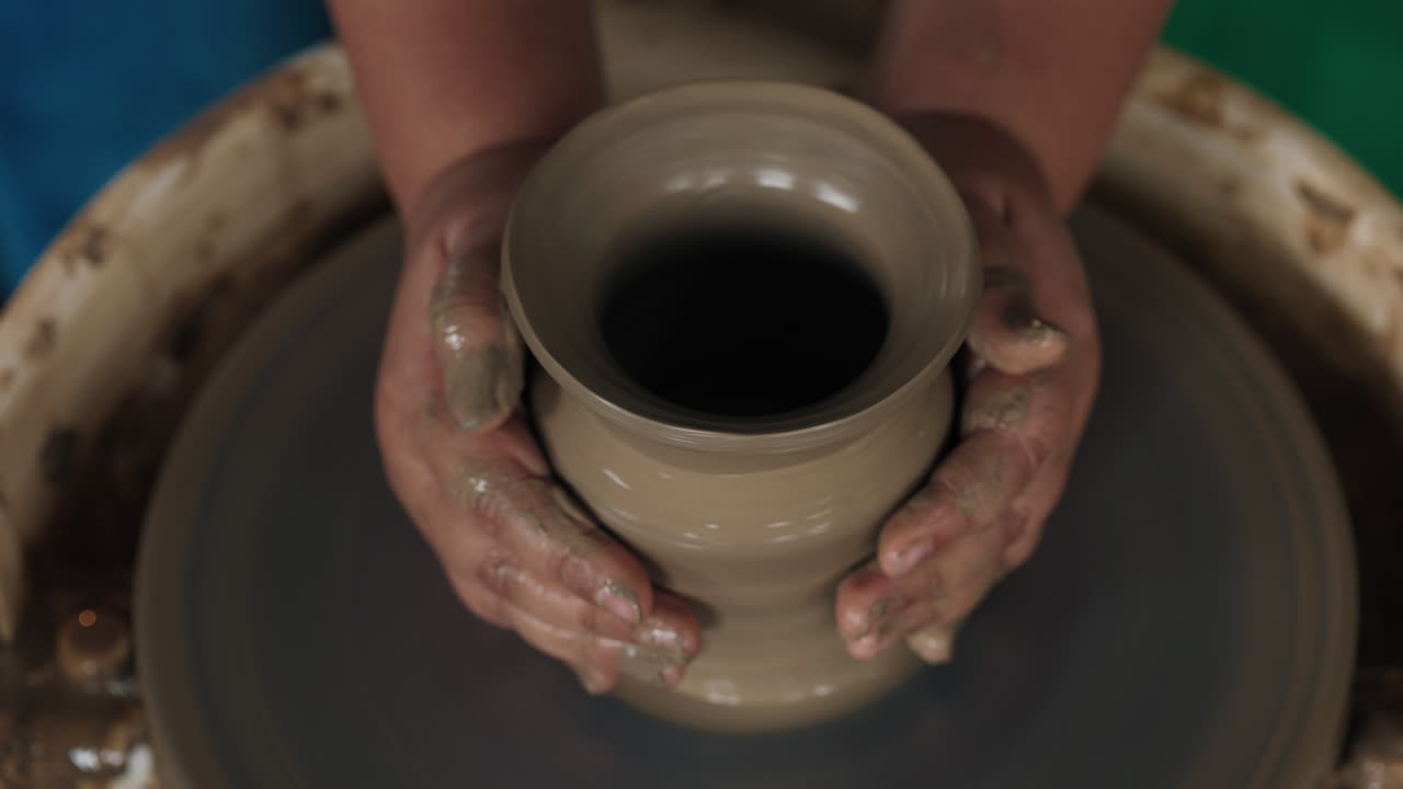 Hands shaping a vase on a pottery wheel