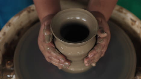 hands shaping a vase on a pottery wheel