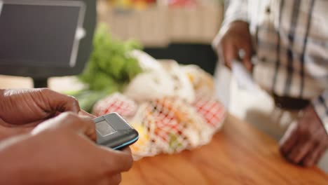 sección media de un hombre afroamericano de alto nivel pagando con tarjeta de crédito en una tienda de alimentos saludables, cámara lenta