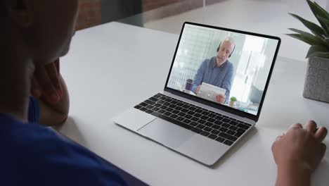 Mid-section-of-african-american-woman-having-a-video-call-with-male-colleague-on-laptop-at-office