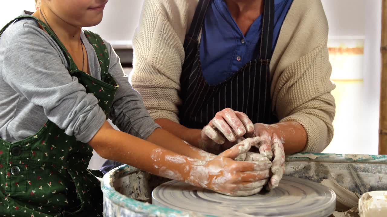 una alfarera ayudando a una niña