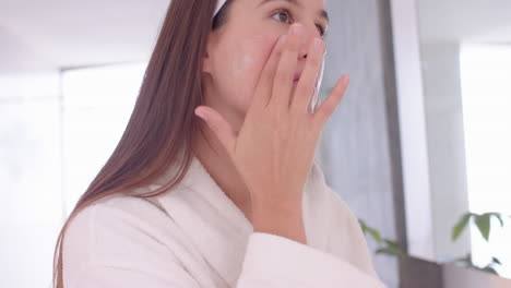 applying face cream, woman in bathrobe enjoying spa treatment at home
