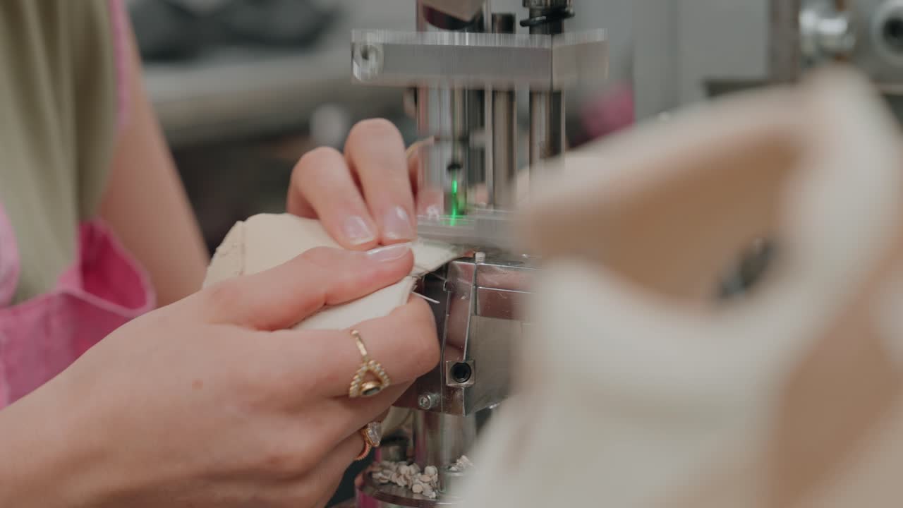 hands guide shoe as machine perforates eyelets with precision